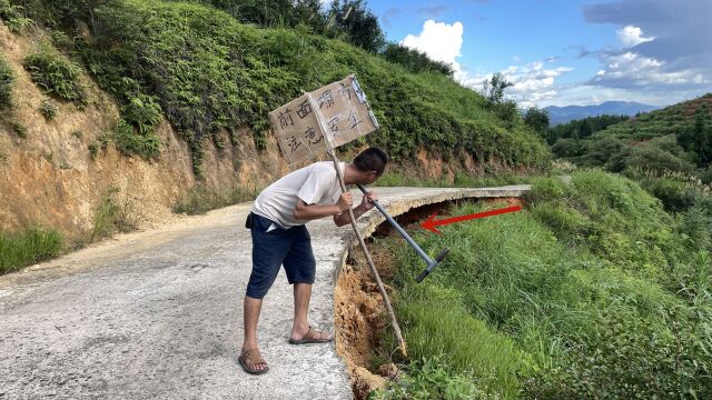 大雨导致道路突现塌方,小伙看到悬空的路基被吓坏了,立起警示牌