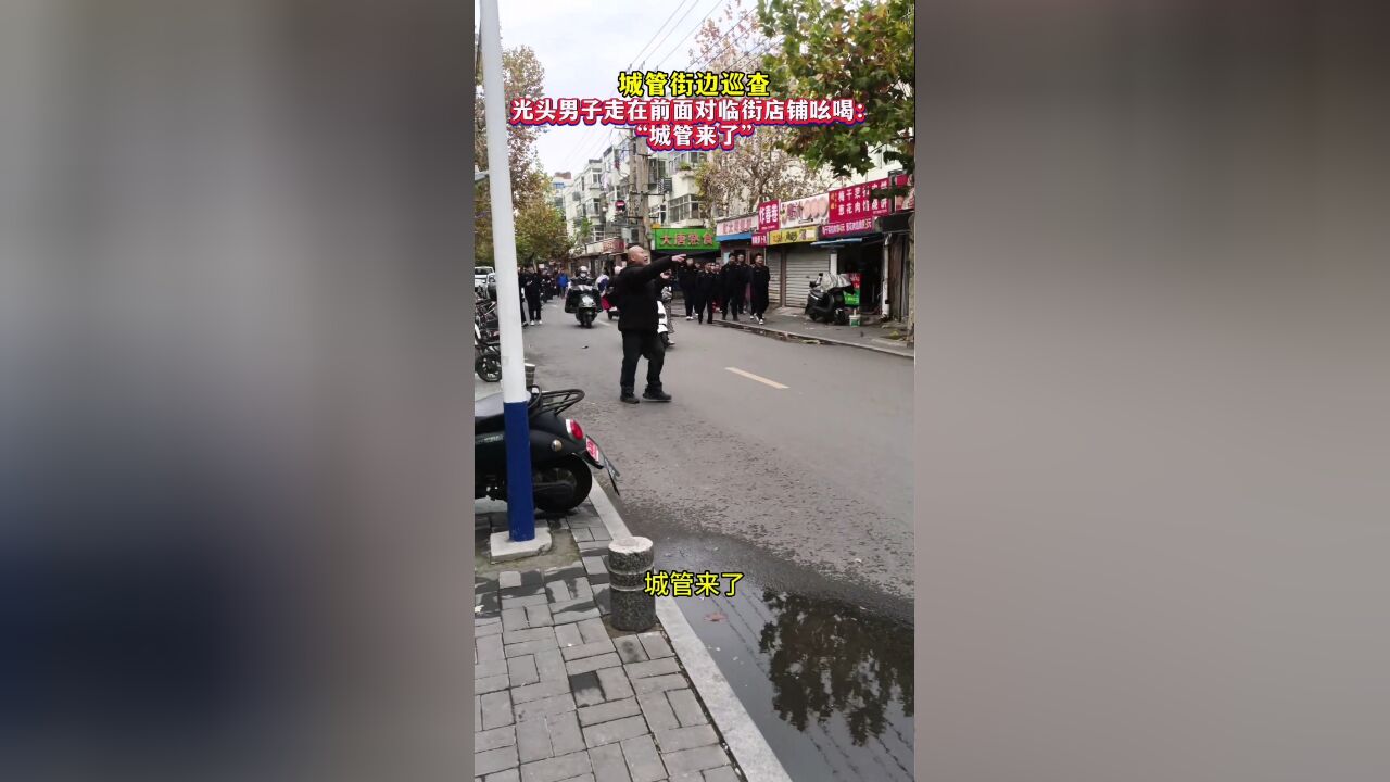 城管街边巡查,光头男子走在前面对临街店铺吆喝:城管来了