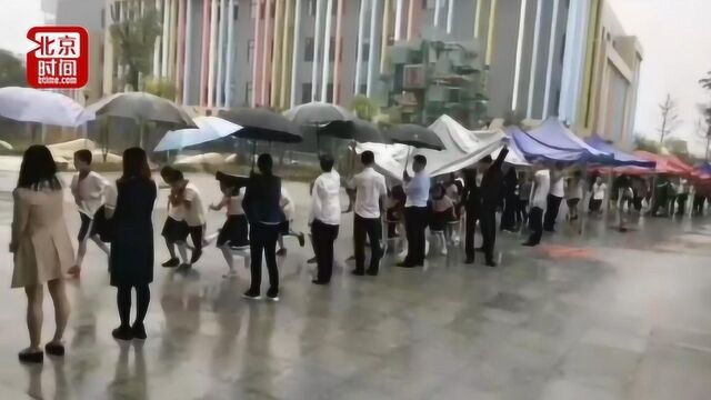 暖心!小学晨会突降大雨 老师撑伞为学生搭建防雨通道回教室