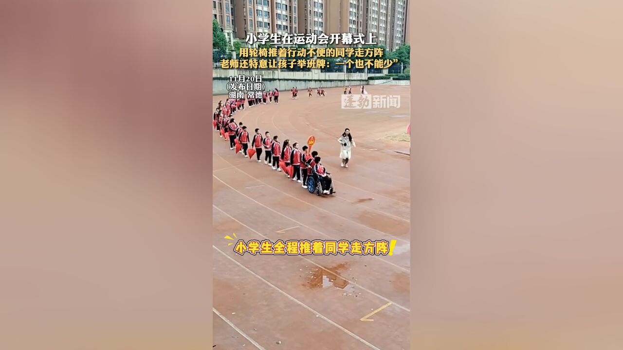 小学生在运动会开幕式上,用轮椅推着行动不便的同学走方阵