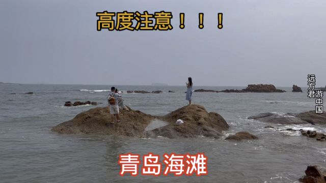 实拍青岛海滩,有人在水中拍照,海浪总是来的猝不及防