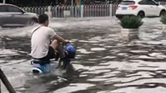 画风太高能!大雨后街道变河道,男子把电动车当“巡洋舰”骑!