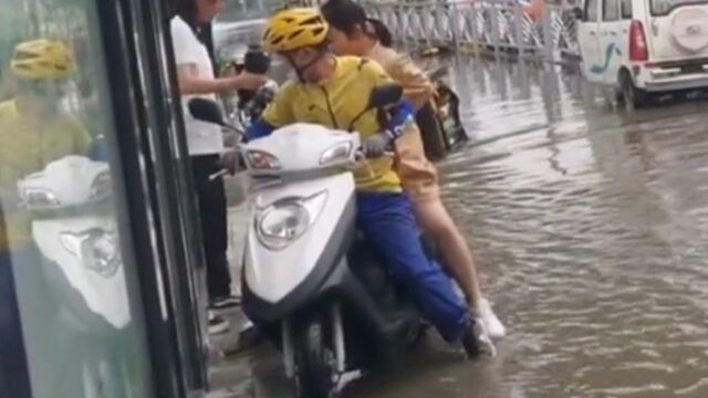 雨后路上积水成河,外卖小哥化身摆渡人,暖心接大家“过河”!