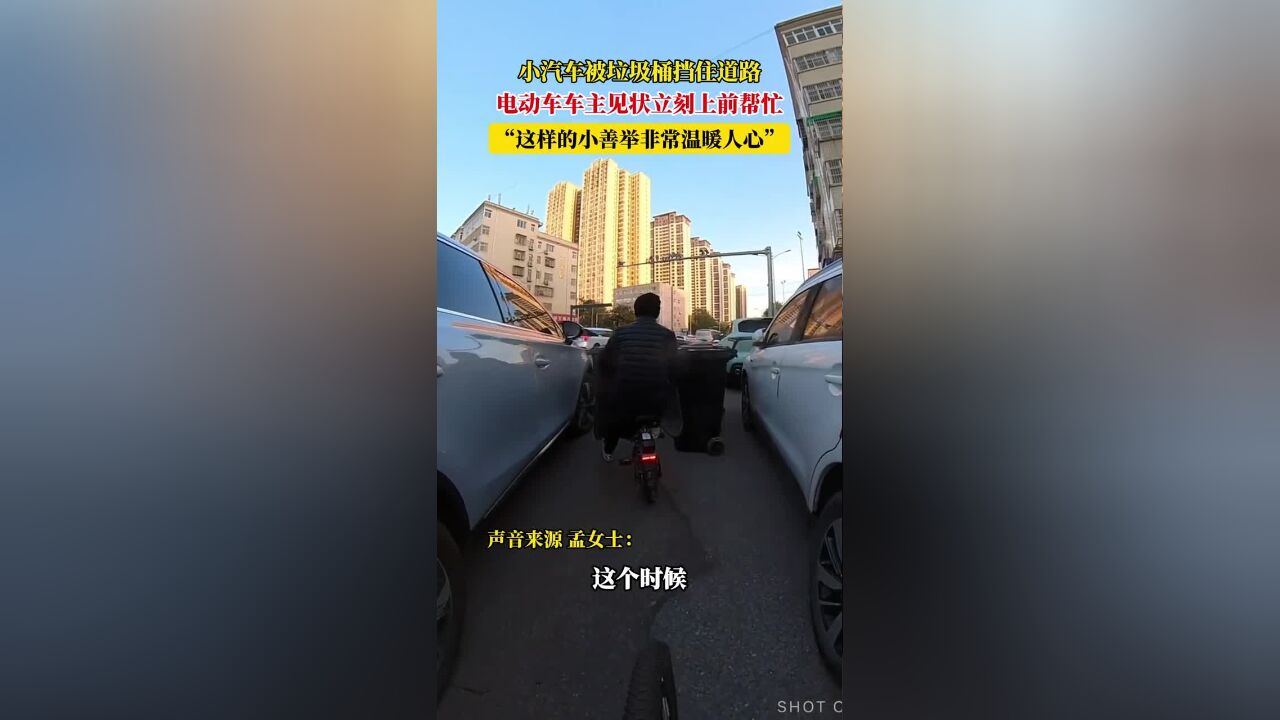 小汽车被垃圾桶挡住道路,电动车车主见状立刻上前帮忙,“这样的小善举非常温暖人心”