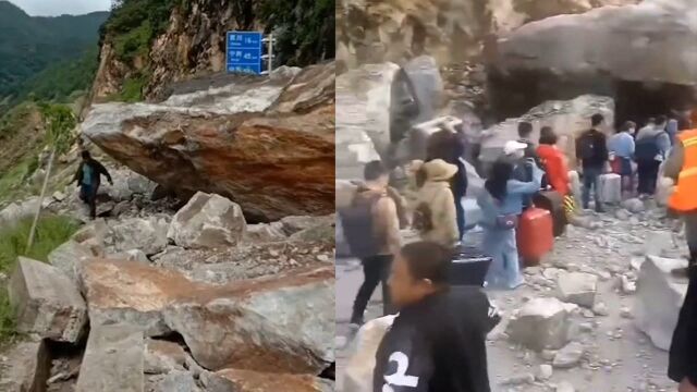 云南丽江突发山体塌方,巨石滚落隔断道路,被困人员扎堆步行通过