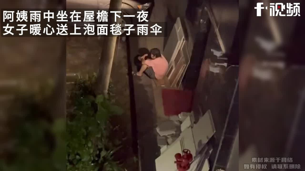 阿姨雨中坐在屋檐下一夜女子暖心送上泡面毯子雨伞