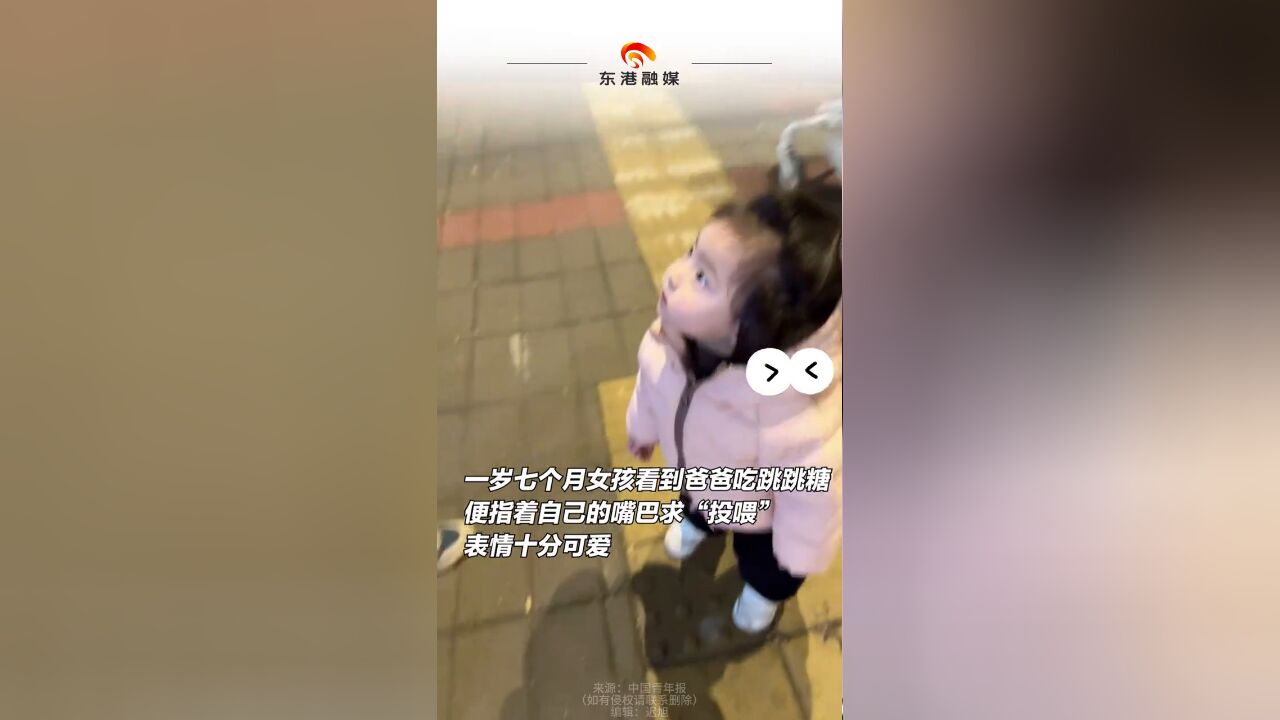 女孩看到爸爸吃跳跳糖 便指着自己的嘴巴求“投喂”