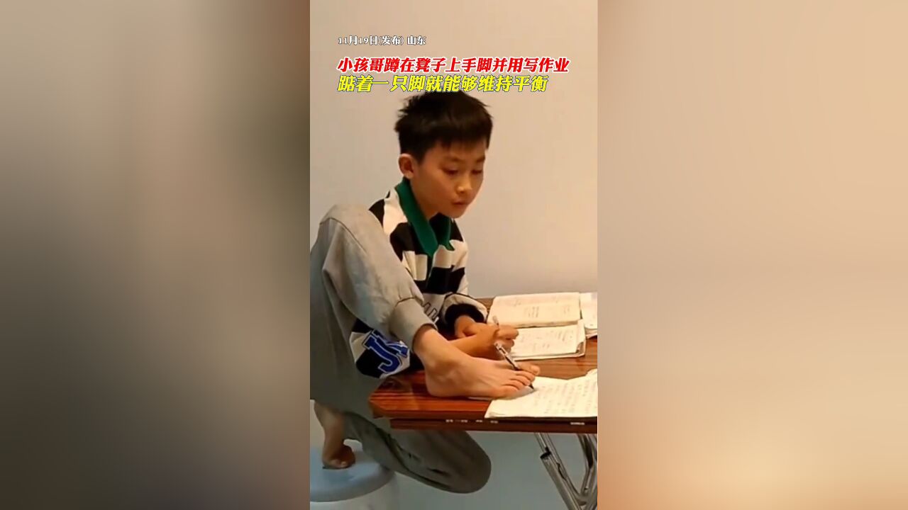 小孩哥蹲在凳子上手脚并用写作业,踮着一只脚就能够维持平衡.