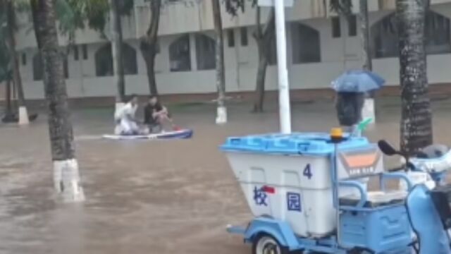 海口连降暴雨造成积水,海南大学校园内,男生划桨板通行