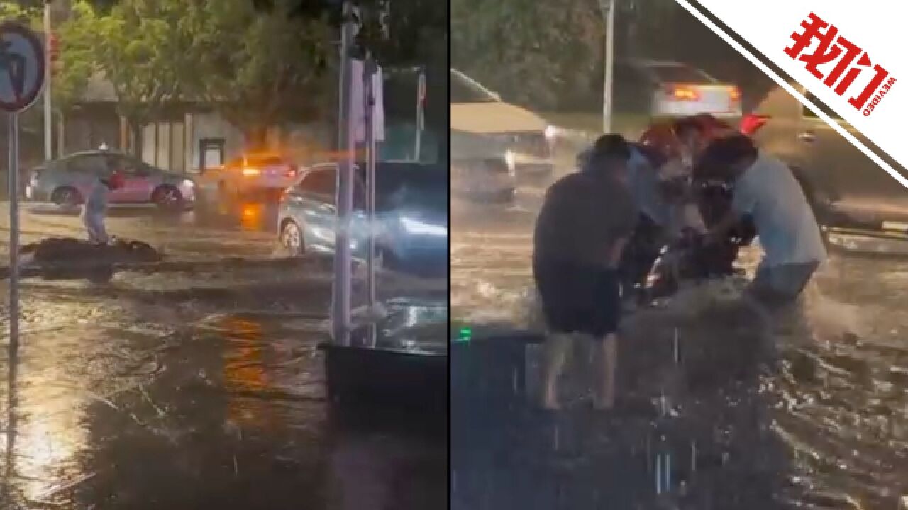 贵州兴义暴雨内涝:汽车积水中行进 市民涉水救援倒在激流中的摩托车