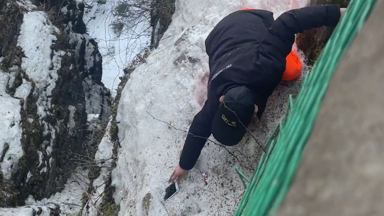 峨眉山工作人员脚踩冰雪沿着悬崖帮游客捡手机 景区回应