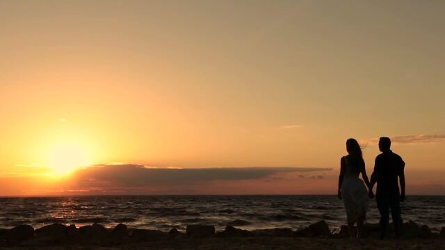 实拍海边风景夕阳下情侣手牵手在海边看日落