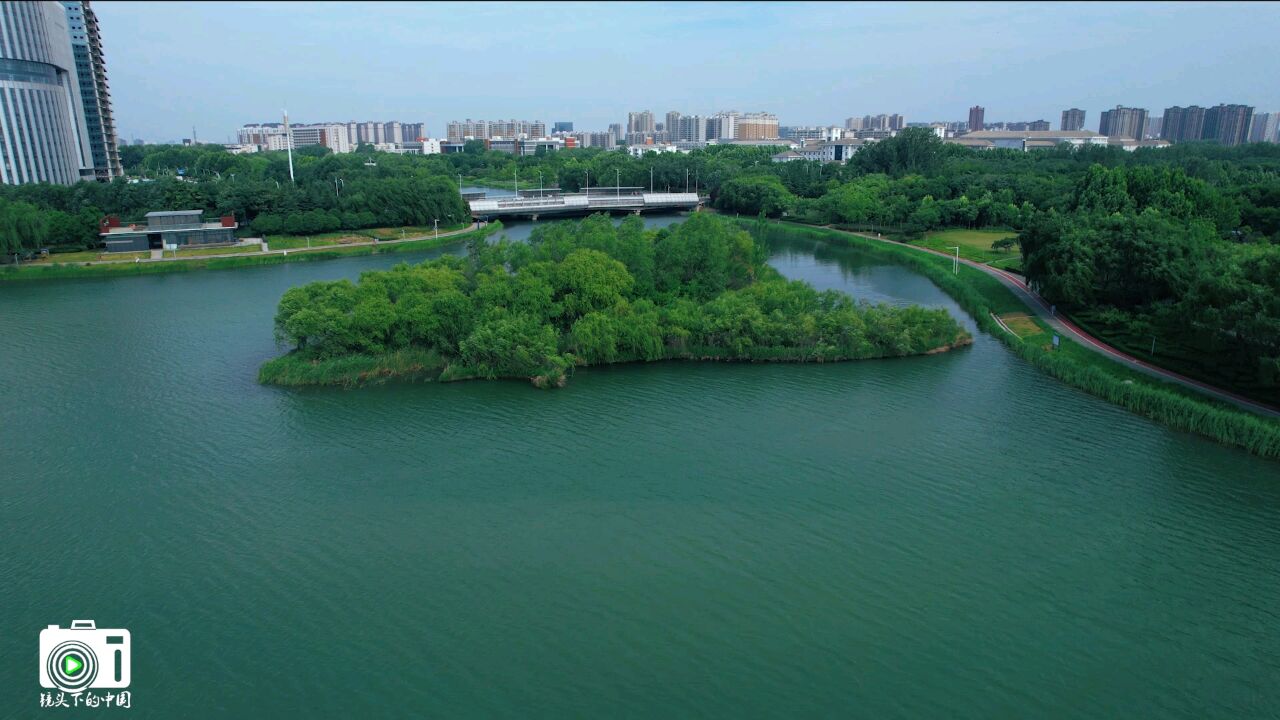 郑州龙子湖湖面波光粼粼,两岸风光如画游人如织湖边垂柳依依