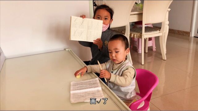 俩小孩在学习写字,还交头接耳的,好像我上学的时候抄作业