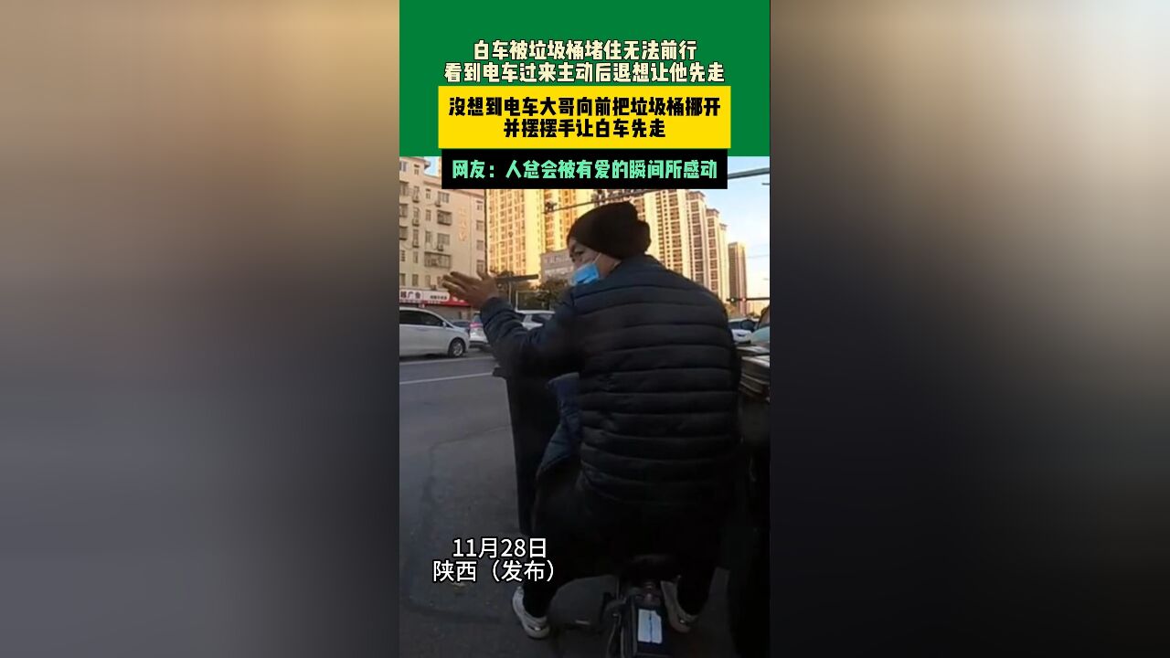 11月28日陕西 白车被垃圾桶堵住无法前行,看到电车过来主动后退想让他先走,没想到电车大哥向前把垃圾桶挪开,并摆摆手让白车先走,网友:人总会被...