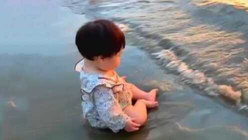 宝宝们坐在海边，直愣愣的看着海浪，海浪冲过来时爸妈都笑抽了