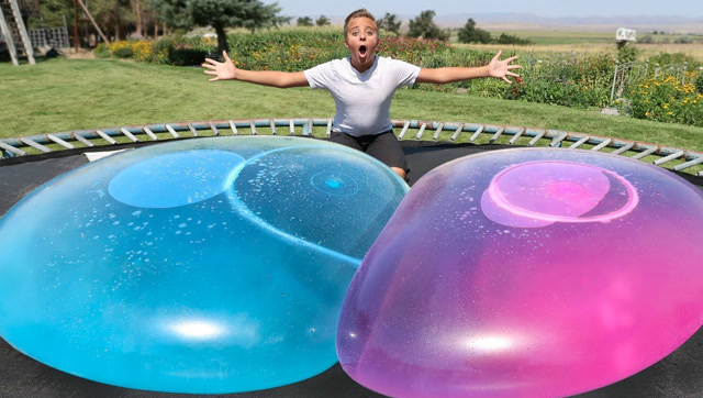 挑战压破放在蹦床上巨大的水球,熊孩子们玩得可开心了