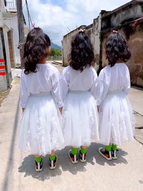 穿着白裙子的三个小女生,回头后才发现是三胞胎,看着好像啊