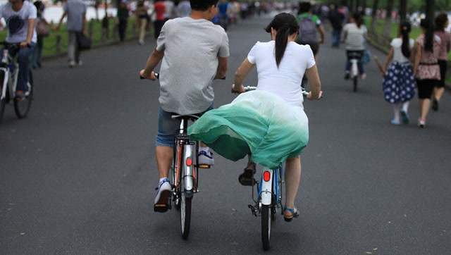 骑电动车的女子,裙子被卷入车轮出丑了