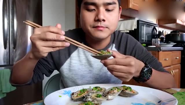 越南小伙吃扇贝,佐料加了不少,吃起来很对胃口