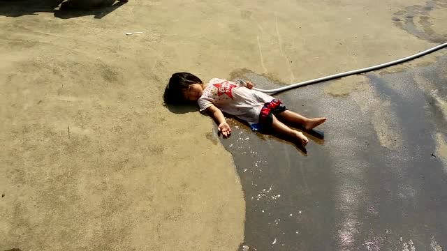 天气太热了,小女孩直接倒在地上玩水,妈妈以为中暑吓坏了