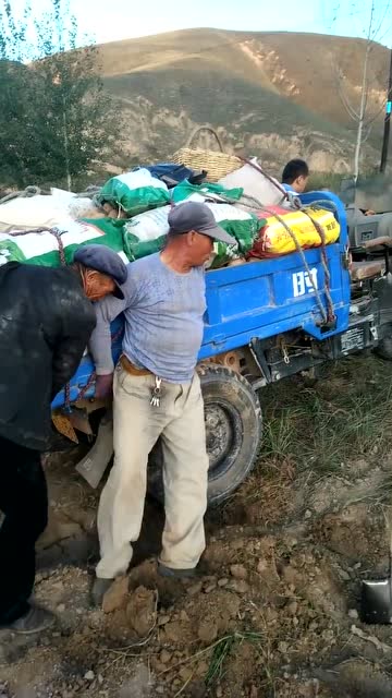 农民大爷干活真辛苦,三轮车陷到地里,竟然几个人抬着出来