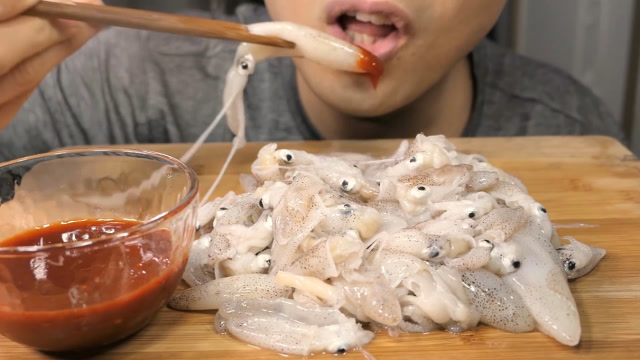 新鲜的迷你小鱿鱼大胃王小哥哥倒了些酱料下去就生吃厉害