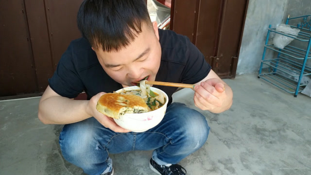 吃面蹲着咥,还加一个馍,一看就是陕西小伙,吃得真过瘾