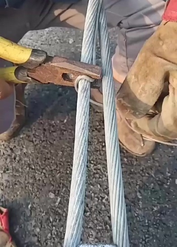 工人师傅正在用铁丝制作缠绕绑扎95平方钢铰线制作的电杆拉线上把过程