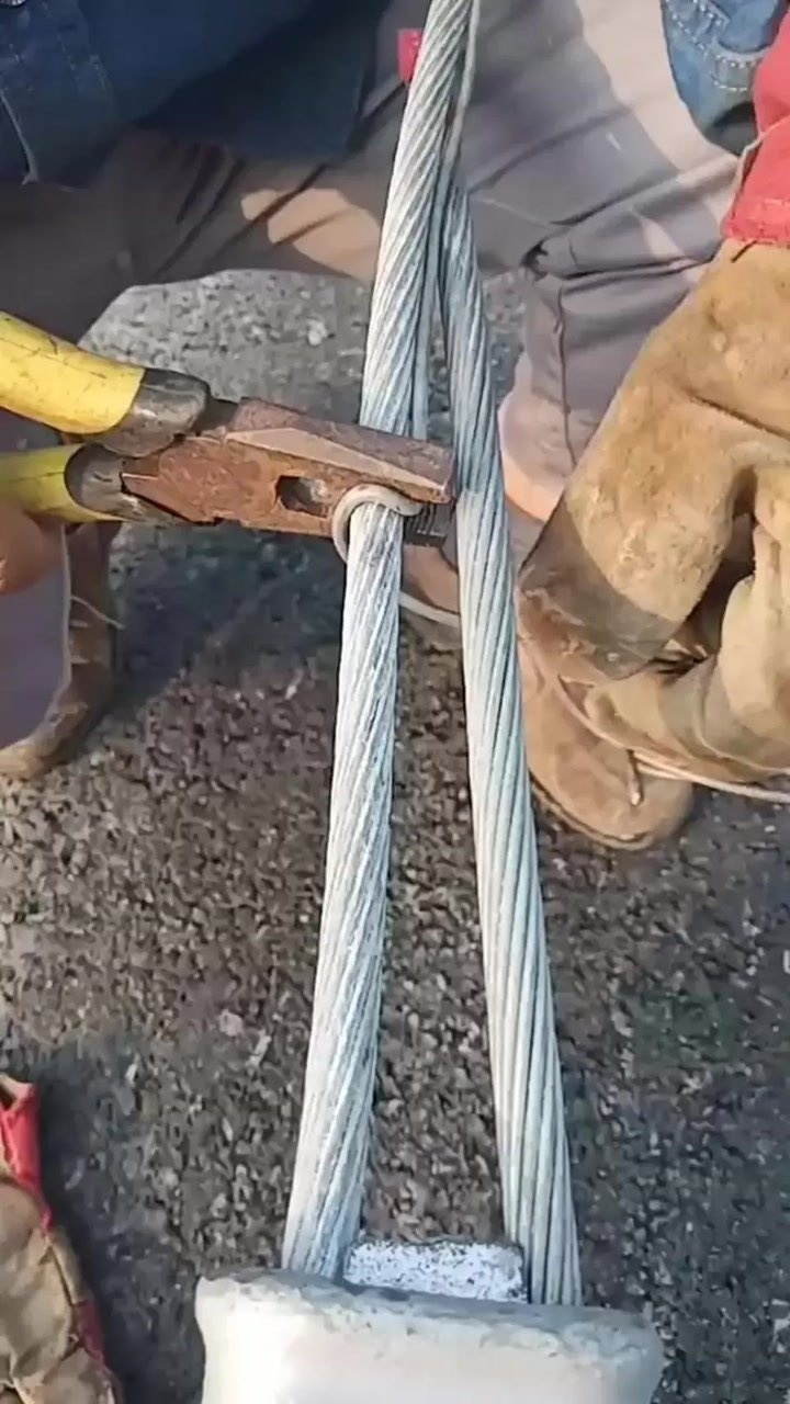 工人师傅正在用铁丝制作缠绕绑扎95平方钢铰线制作的电杆拉线上把过程