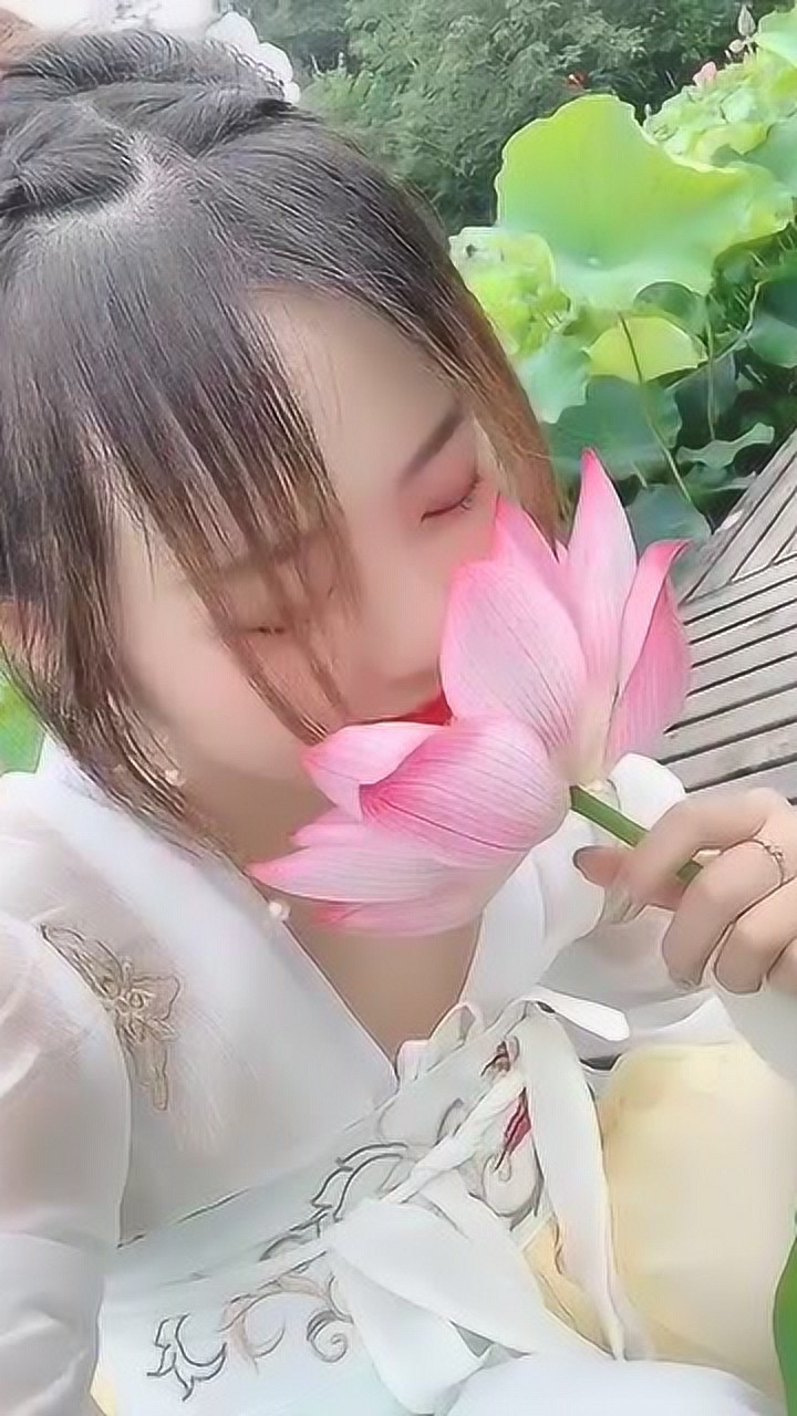 这位清纯可爱的姑娘她拿着荷花的样子非常的优美