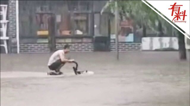 河南新乡暴雨过后街道成河 男子“蹲骑”电动车水中穿行