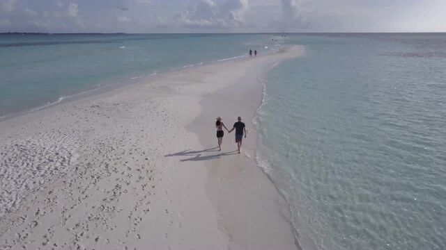 Couple Walking on a Beach Filmed with a Drone