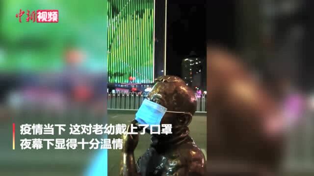 路人给兰州地标雕塑“热冬果”戴上口罩