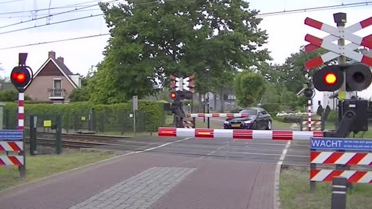 荷兰铁路交叉道口红灯闪烁驶过一列货运列车