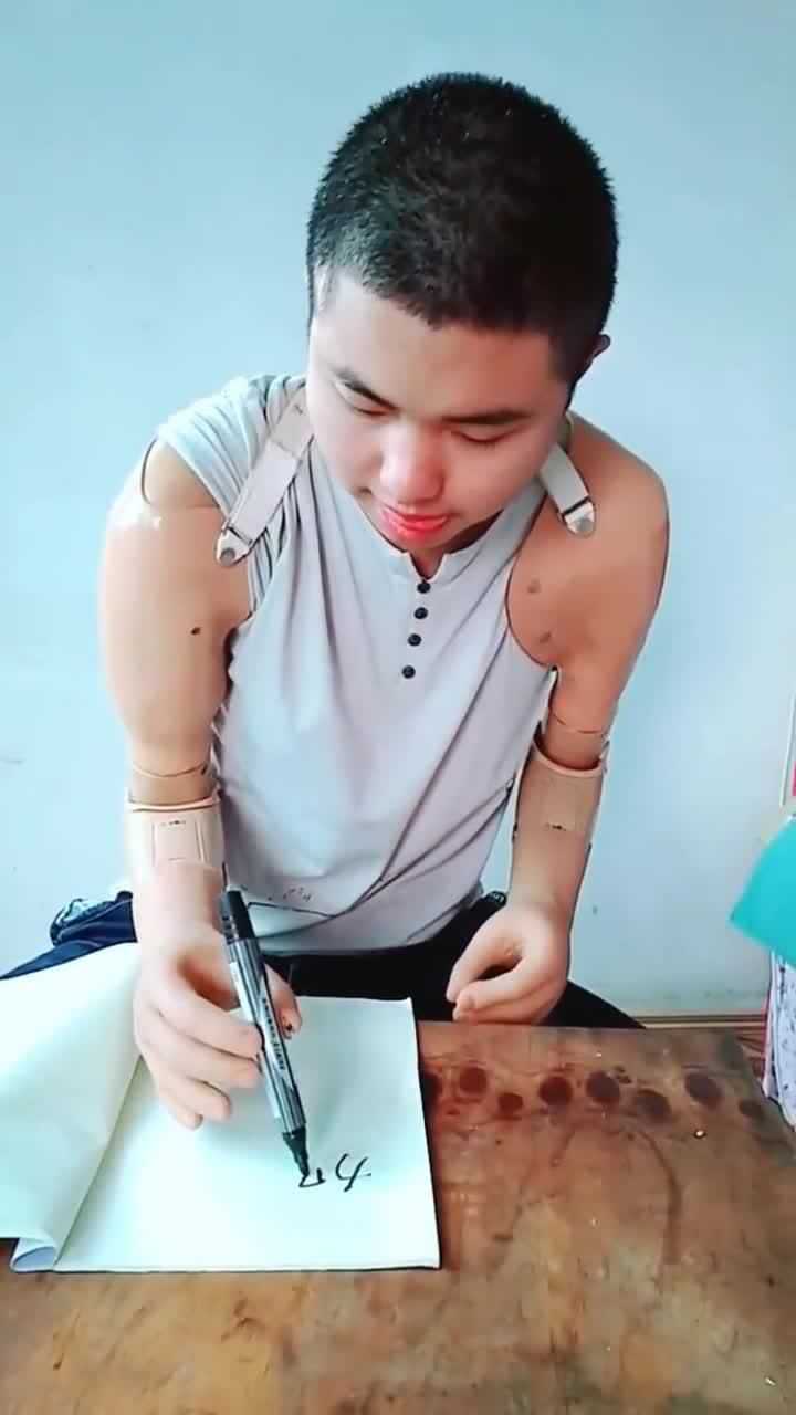 无臂男孩儿戴着假肢练习写字网友写得还挺好的一定要加油啊