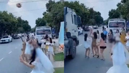 新娘路边扔手捧花众人争抢，一人被挤路中间与疾驰货车擦肩而过