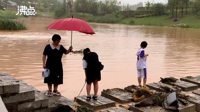 河南汝州暴雨后家长带孩子河里捕鱼 旁边就是预防溺水警告牌