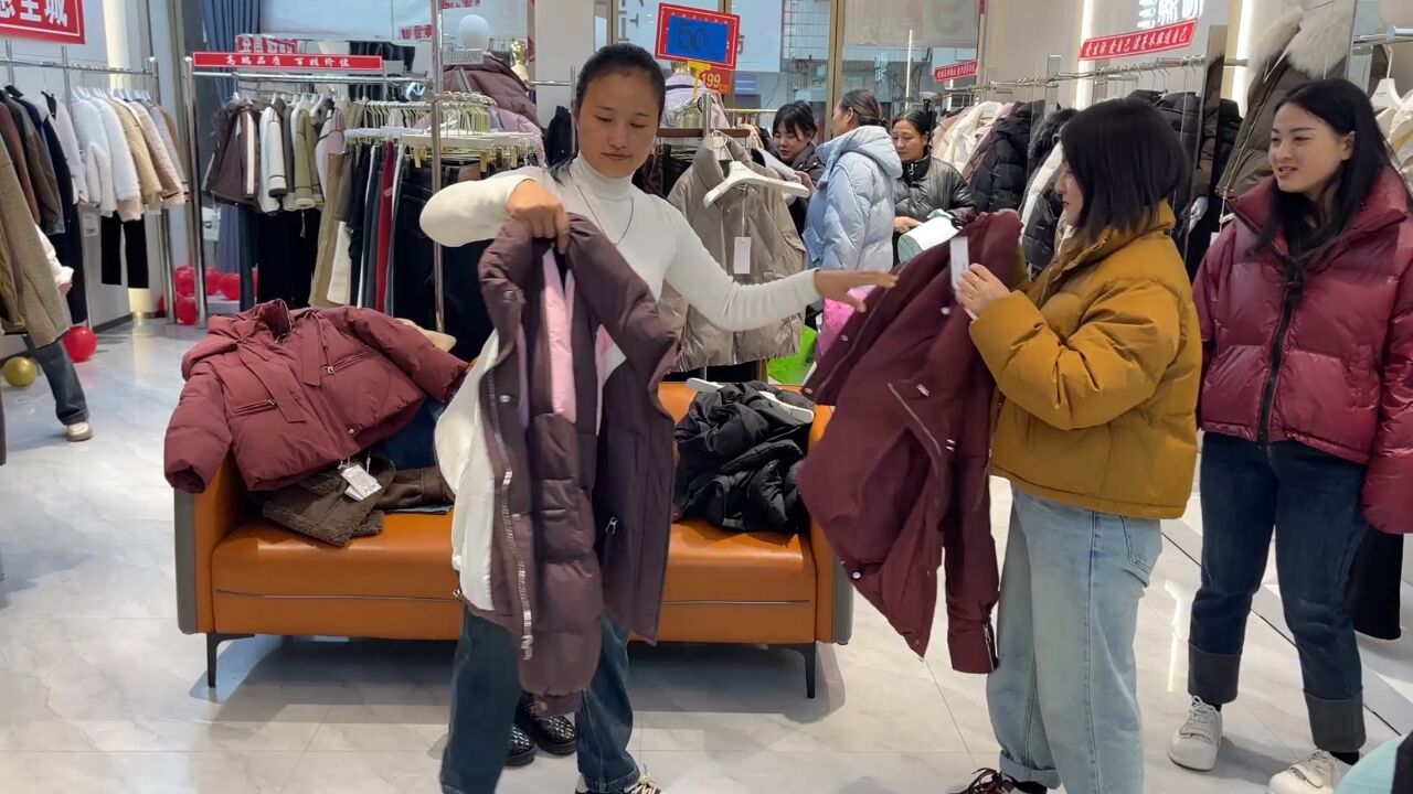 天变冷了,小伙带媳妇去买棉袄,媳妇尝试穿个新颜色,挺合适