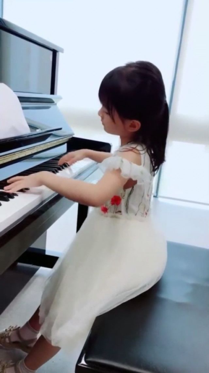 8岁小女孩弹钢琴,穿着白裙子,好像一个小公主