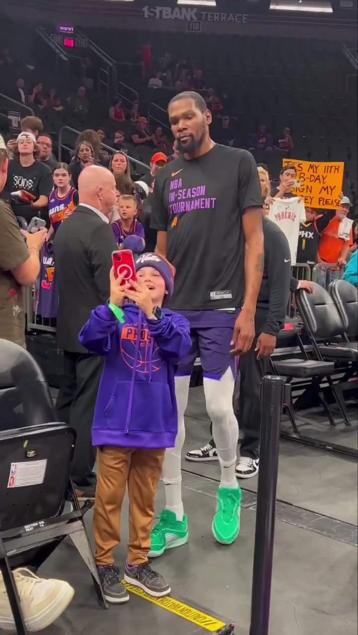 暖心的优质偶像!杜兰特主动站在小球迷身后,并接过手机与他合影.