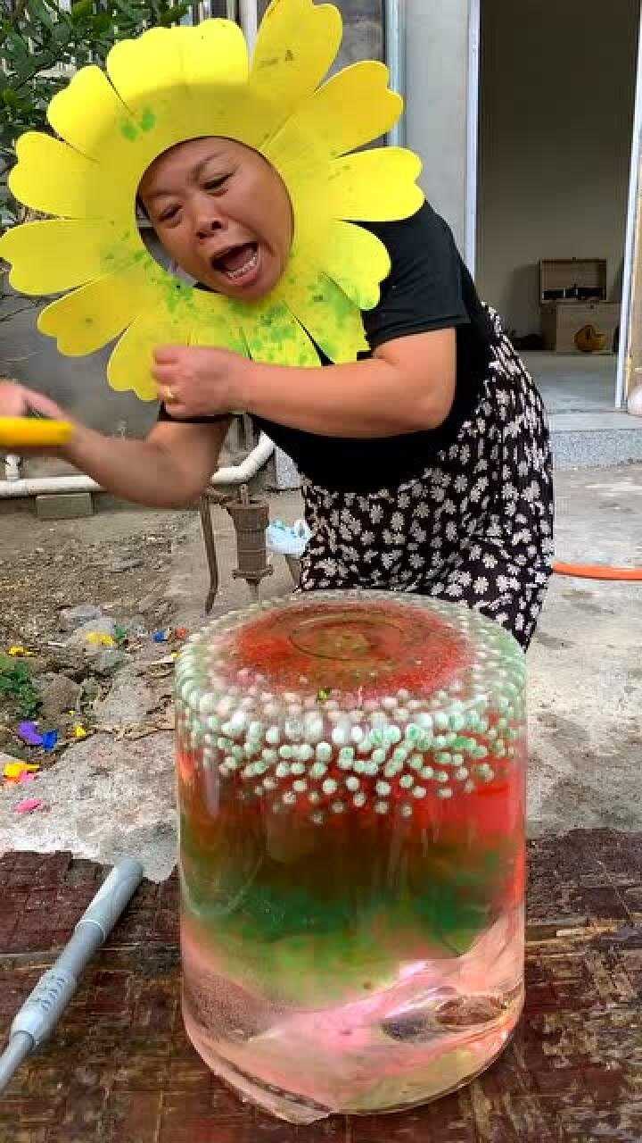 大妈戴着向日葵头饰用锯子砸冰.