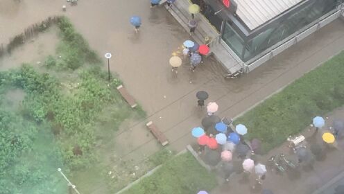 防汛沙袋铺出人行通道 地铁工作者雨中帮扶乘客