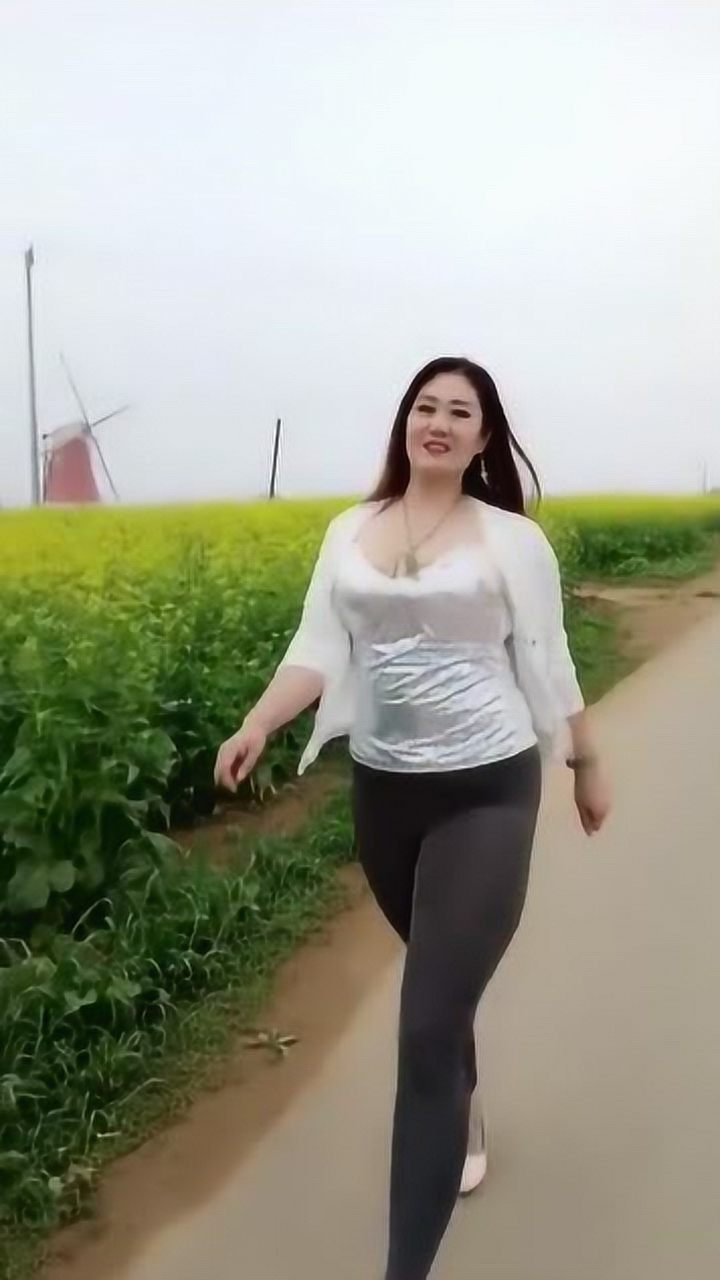 美女街拍:肥硕丰满的东北大姐,在油菜地里走秀,韵味十足!