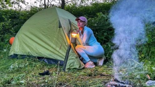 野外露营：年轻女子独自过夜露营在帐篷里放松