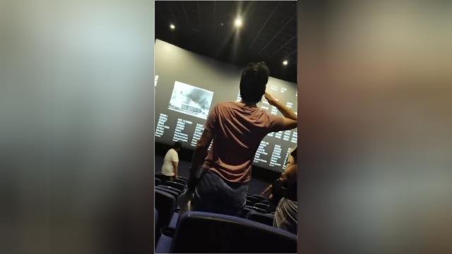 电影结束后女子突然起身向荧幕敬礼面对着满满的抗日英雄照片