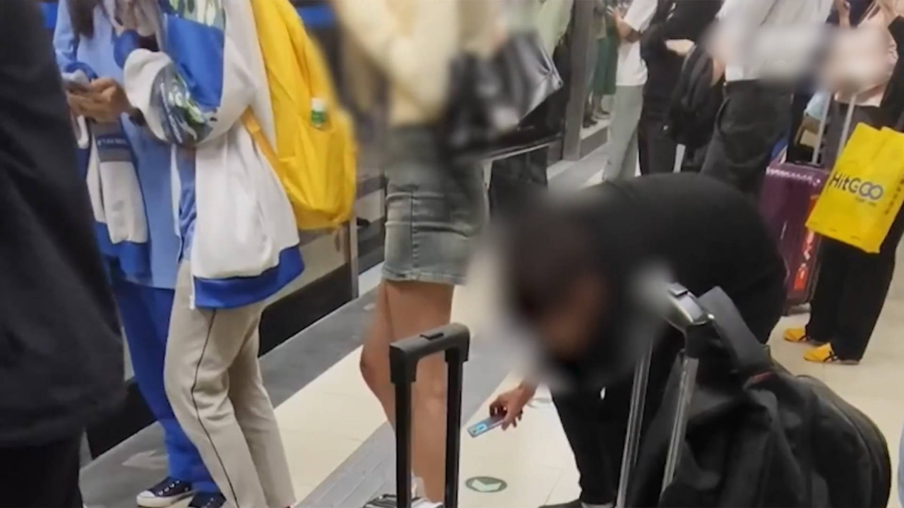 男子地铁站佯装弯腰提鞋用手机偷拍女生裙底,被其他乘客用手机记录并
