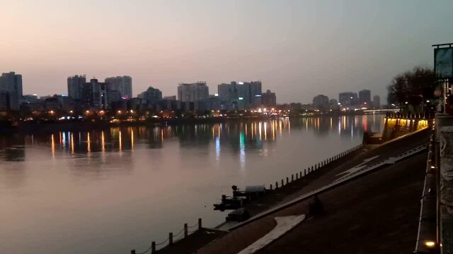 城市的夜景,沿江大道夜钓的,划船网鱼的组成一幅图画