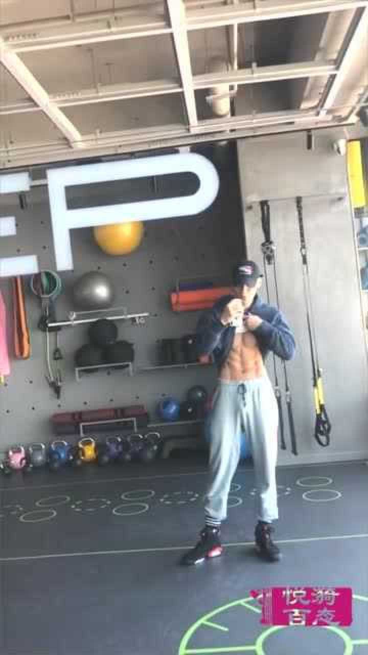 肌肉型男在健身房的落地镜前撩起外套,露出结实的腹肌和鲨鱼线