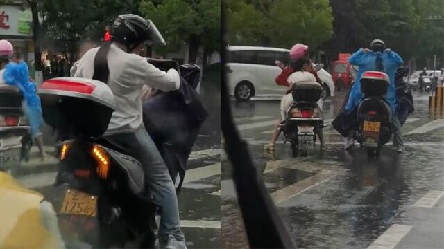 突降大雨,妈妈骑车带娃被雨淋湿,好心路人脱掉雨衣给孩子穿上